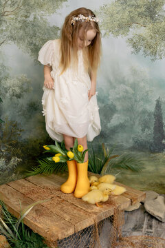 Child girl holding tulips with ducklings, spring portrait with soft green background