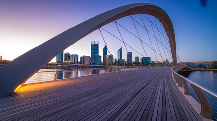 Naklejka premium A wide angle architectural photograph captures a bridge and cityscape at sunset