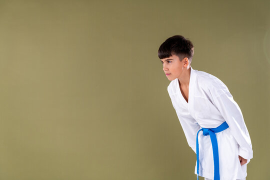 Karate practitioner wearing a white uniform and blue belt performs a respectful bow before training. The gesture reflects discipline, focus, and traditional martial arts etiquette.