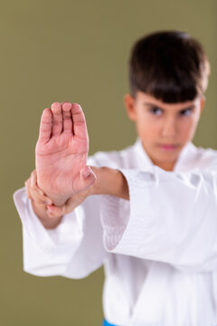 Young martial artist in white uniform performs a defensive hand stance, maintaining concentration and proper alignment during training.