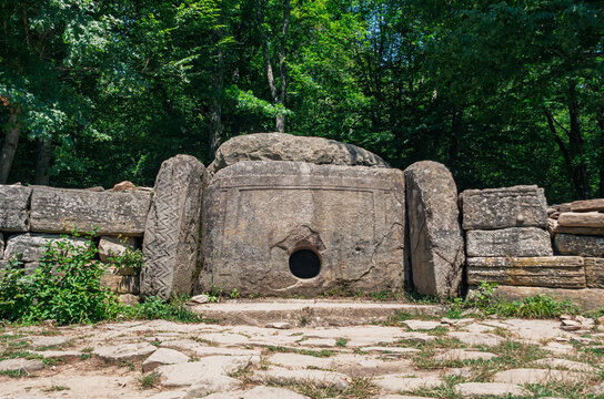 Prehistoric megalithic tomb made of massive stone blocks hidden deep within a vibrant summer forest