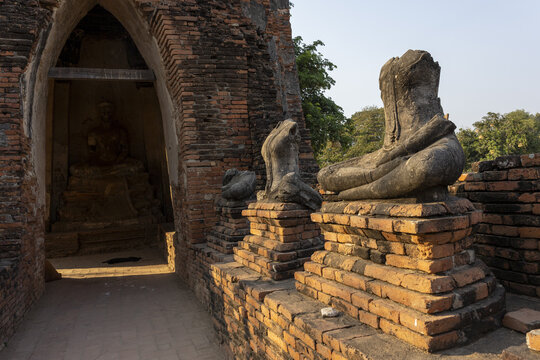 Solemn headless stone buddha statue ruin sitting on an ancient brick pedestal outside temple entrance wat ayutthaya thailand evoking deep tranquil atmosphere