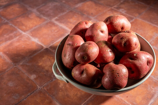 Red skin potatoes in a white ceramic bowl on a tole surface 