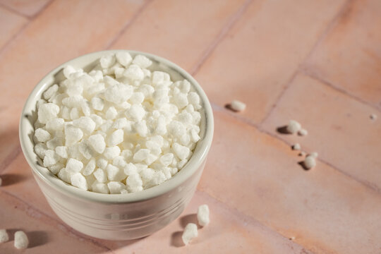 Pearl sugar in a white ceramic bowl on a tile surface 