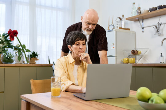 Loving seniors share a joyful moment together while exploring online adventures at home