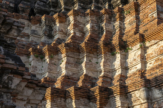 Ancient brick architecture detail from historic Wat Ayutthaya Thailand temple ruins conveying sense of timeless awe with intricate structural patterns shadows and weathered texture
