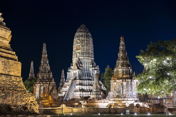 Naklejka premium Illuminated ancient temple ruins wat ayutthaya thailand at night offering serene and awe inspiring view of historical architecture beautifully lit against dark sky highlighting cultural heritage