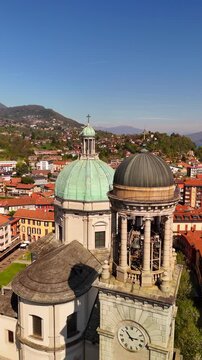 Aerial drone view of Basilica di San Vittore in Verbania Intra, Lake Maggiore. Bell tower and church with aged green copper domes, historic town and lakeside scenery.