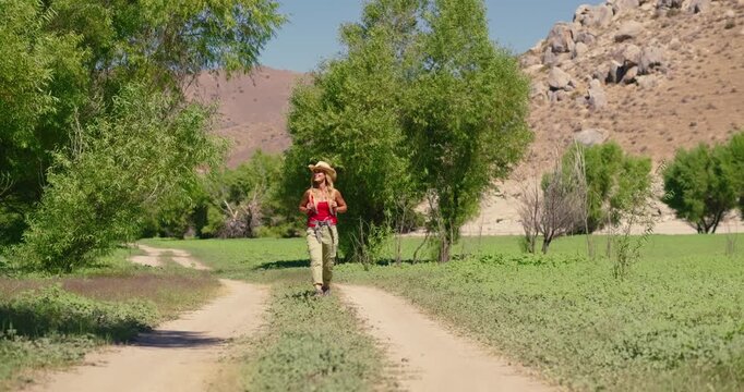 Woman Hiking on Rural Path Under Blue Sky