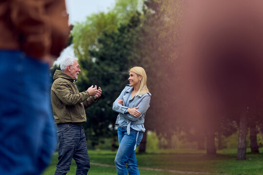 Mature Man and Woman Talking and Laughing in Park During Casual Outdoor Meet-Up