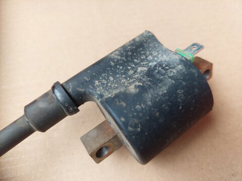 Detailed view of an aged and grimy electrical ignition coil, essential for engine operation and vehicle maintenance