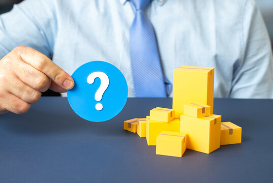 A man holds a question mark near boxes of goods. Questions about cargo transportation and customs clearance arise. Import and export operations require compliance and documentation.