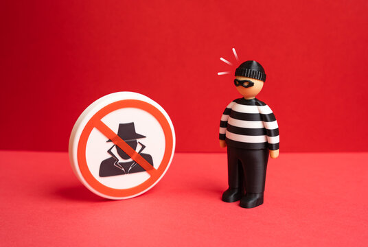 A criminal reacts to a prohibition sign against spies and fraudsters. Countering espionage strengthens security. Protection measures reduce risks from malicious activities.
