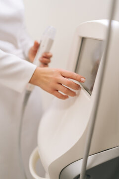 Vertical shot of professional aesthetician performing a microneedling treatment with a specialized device, meticulously adjusting the settings for a rejuvenating skin therapy session.