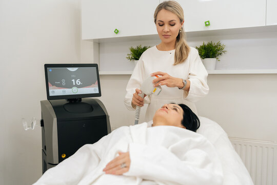 Esthetician performing non invasive SMAS lifting photorejuvenation procedure on woman client neck, modern hardware cosmetology treatment for skin rejuvenation and facelift.