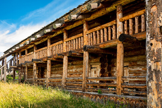 The impressive wooden walls of a reconstructed Old Slavic fortress, made of round, hewn logs. Old barracks and boyar chambers. A bright, sunny day.