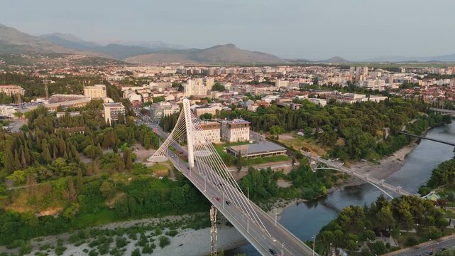 Modern architecture and green parks define the cityscape of Podgorica, Montenegro. Aerial drone shot shows the Millennium Bridge over the Moraca River in Podgorica, Montenegro