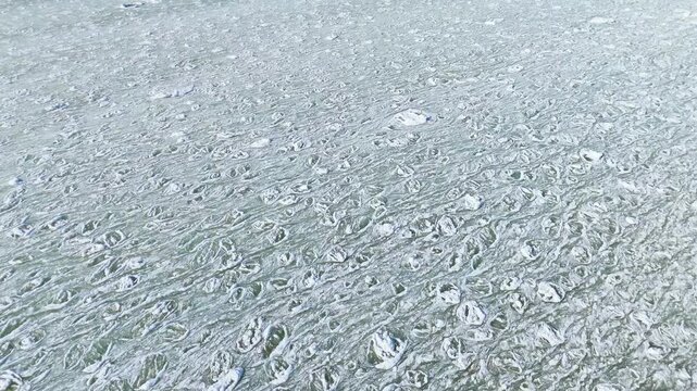 Aerial view of frozen sea with floating ice floes and slush.