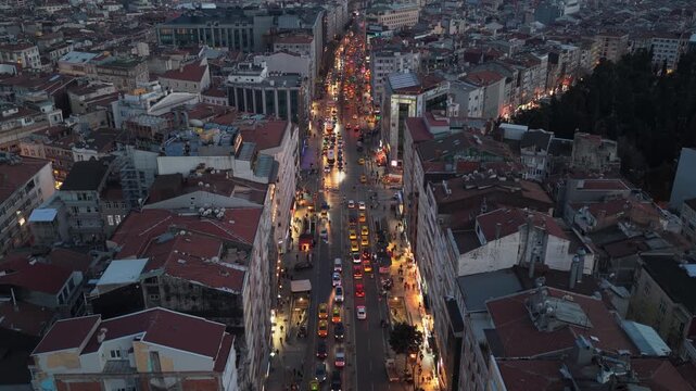 Illuminated Istiklal Avenue in Istanbul at dusk with bustling city traffic, historic buildings, streetlights creating vibrant urban nightscape in Beyoglu district