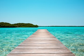 Obraz premium Wooden Dock Extends Over Blue Water Under Clear Sky at Tropical Location