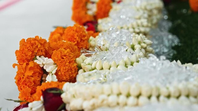 Jasmine Jasminum sambac and marigold Tagetes garlands lying on crushed ice, Songkran festival celebration, Thai Buddhist ritual ceremony background, cultural travel marketing