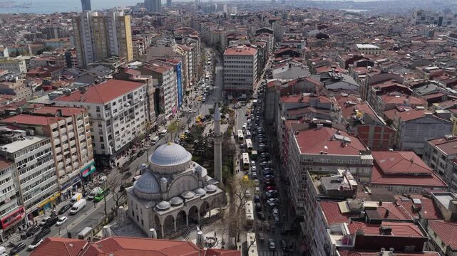 Aerial backwards motion revealing Pertevniyal Valide Sultan Mosque and urban landscape of Aksaray district with city traffic in Istanbul, Turkey