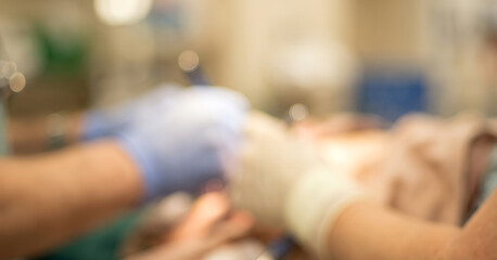 Obraz premium A blurred view of a medical procedure showing hands in gloves assisting a patient, emphasizing the clinical environment and teamwork in healthcare.