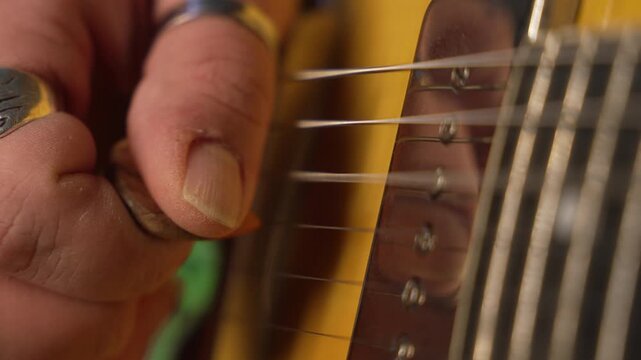 Male musician's hand with rings strumming the strings of a semi-hollow body electric guitar, fa01