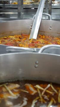Vertical view shows Bun Mang Vit soup boiling inside large metal pot during cooking at market kitchen counter. Traditional recipe.
