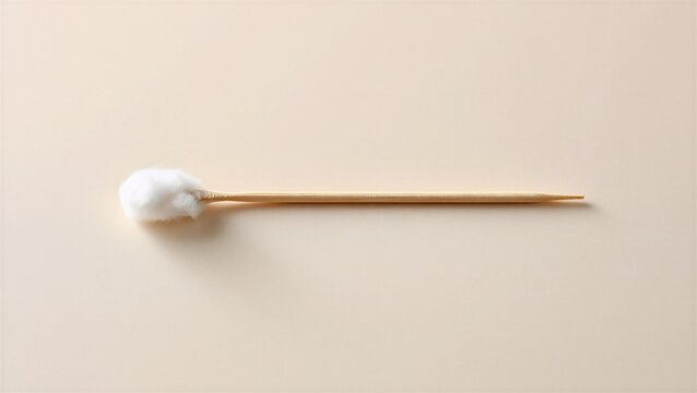 A golden toothpick with a cotton ball, softly lit on a neutral background, expressing minimalism and simplicity.