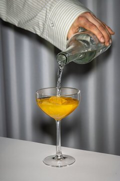 Hand fills water in glas with juice