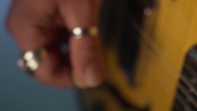 Male musician's hand with rings strumming the strings of a semi-hollow body electric guitar, fa01