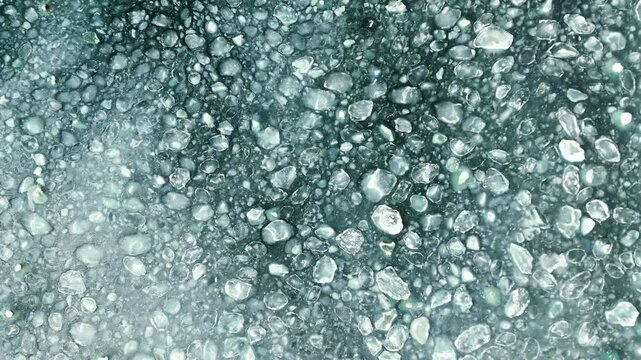 Aerial view of frozen sea with floating ice floes and slush.