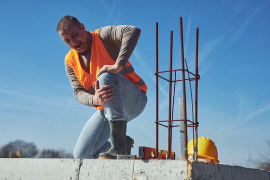 Construction worker having a accident and injured knee and leg on a construction site outdoors.