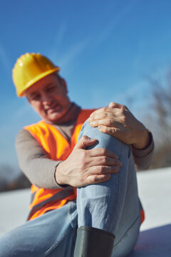 Construction worker having a accident and injured knee and leg on a construction site outdoors.