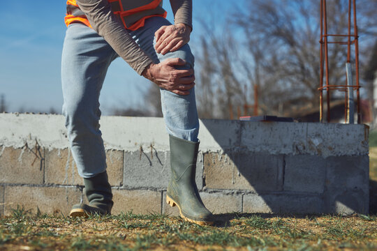 Construction worker having a accident and injured knee and leg on a construction site outdoors.