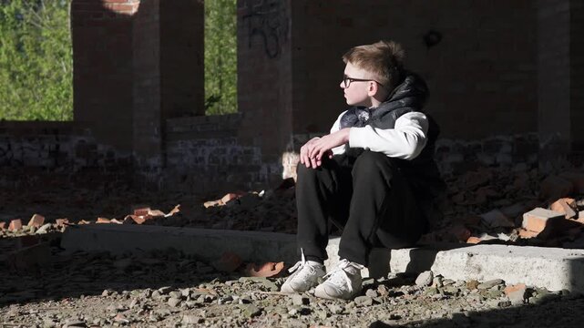 A teenage boy sits alone in an abandoned brick building after school, reflecting feelings of depression and bullying. 