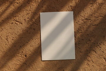 Obraz premium Blank Summer Greeting Card invitation Mockup in Sunlight. Palm Leaves Shadow overlay. Ochre textured stone Background. Neutral Branding Template, Elegant Branding Wedding Stationery. Flatlay, top view