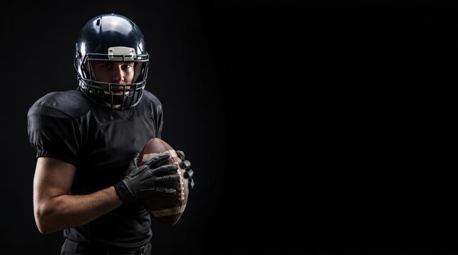 Professional male American football player in black uniform holding ball for cinematic sports portrait