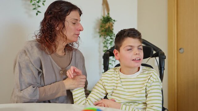 Mother supporting son with cerebral palsy during therapy session