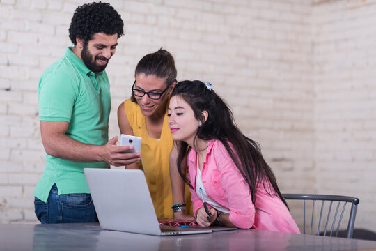 Young Arab startup team collaborating in a creative coworking office with laptop and smartphone