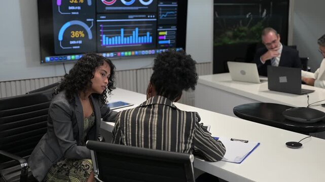 Diverse senior business executives discussing global corporate strategy during a late night board meeting in a modern office. Professional management team collaborating and negotiating with laptops.