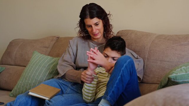 Mother playing with disabled son with cerebral palsy on sofa