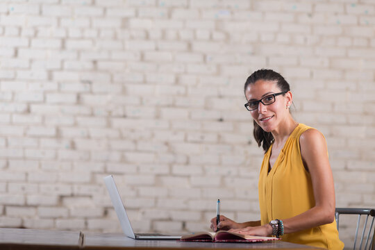 Young woman entrepreneur working at laptop in a startup coworking open office space