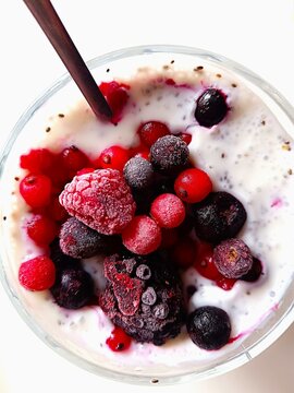 Frozen red forest berries in greek yogurt with chia seeds in a glass bowl for the desert fruit and food background 