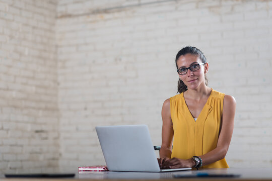 Young professional woman working on laptop in creative startup coworking open office space