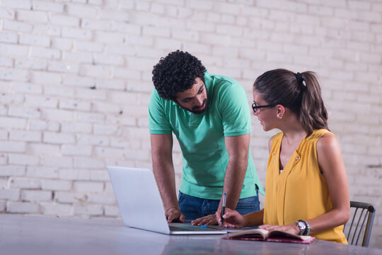 Young professionals collaborate in a casual coworking space over laptop and notebook