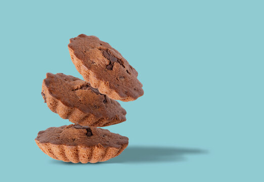 Three chocolate muffins flying on a blue background, space for text