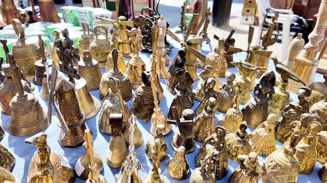 Close-up of a vast collection of vintage brass bells at a flea market.
