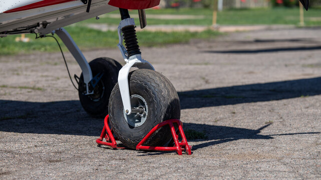 Close-up of light aircraft landing gear with red wheel chocks